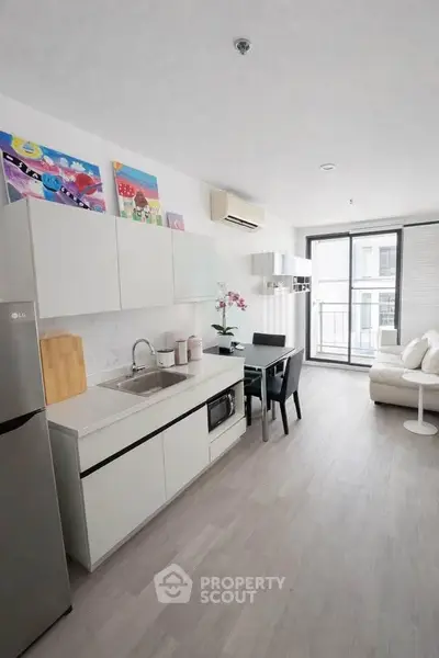 Modern open-layout kitchen with sleek design and balcony access in a stylish apartment.