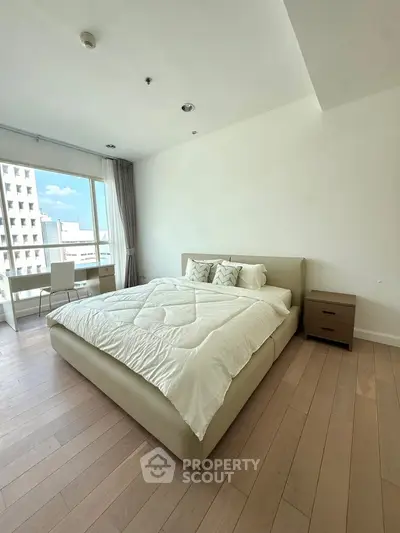 Spacious bedroom with modern decor and large window offering city view