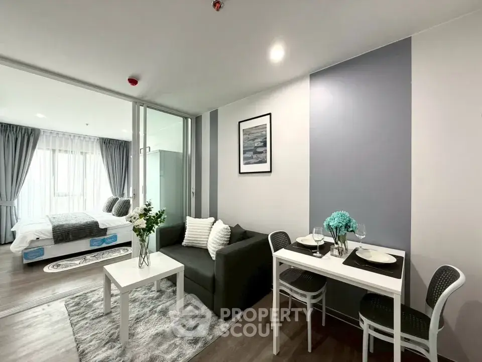 Modern open-plan living room with dining area and bedroom in a stylish apartment.