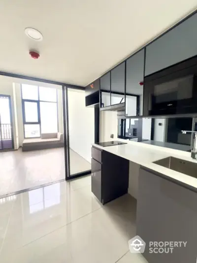 Modern kitchen with sleek cabinetry and open layout leading to a bright balcony.