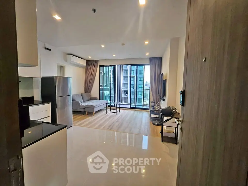 Modern open-plan living room with sleek kitchen and large windows offering city views.