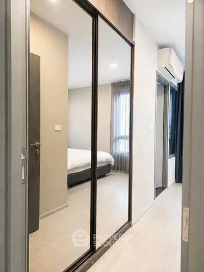 Modern bedroom with mirrored closet doors and sleek air conditioning unit.