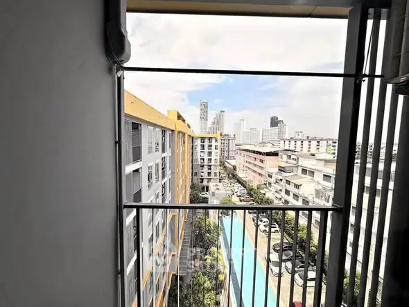 Stunning city view from a high-rise balcony overlooking a pool and urban skyline.