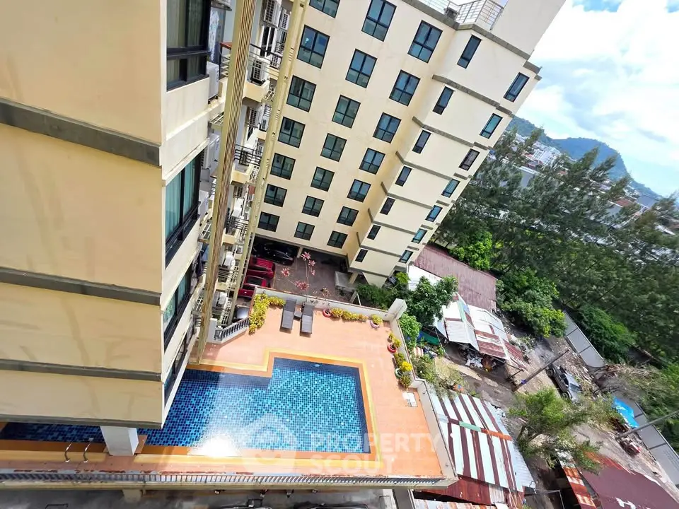 Stunning aerial view of modern apartment building with inviting pool and lush surroundings.