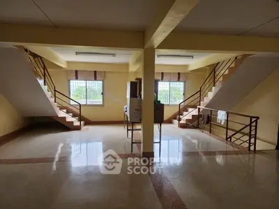 Spacious interior with dual staircases and large windows offering natural light.