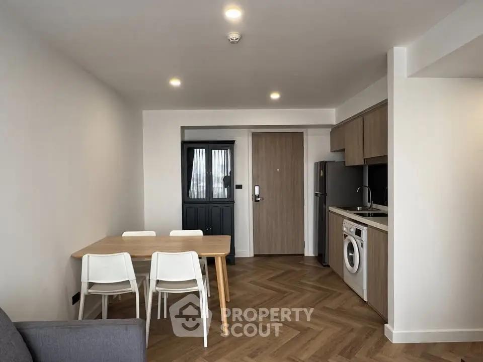 Modern apartment interior with open kitchen and dining area featuring wooden flooring and sleek design.
