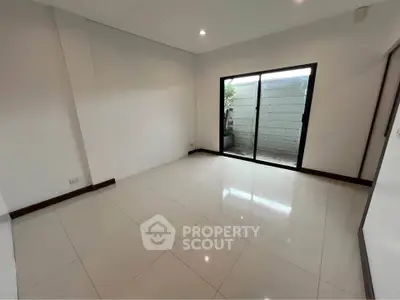 Spacious empty room with sliding glass doors leading to a small outdoor area.