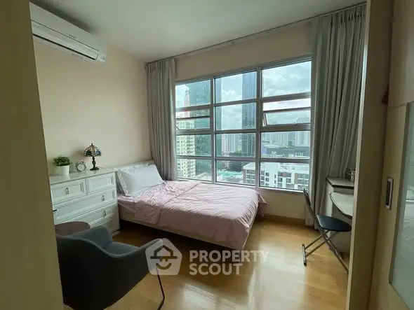 Bright bedroom with city view, featuring cozy bed and modern furnishings.