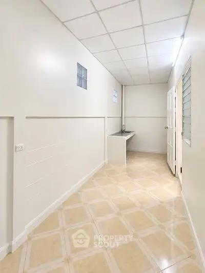 Spacious utility room with tiled flooring and modern sink, ideal for laundry or storage needs.