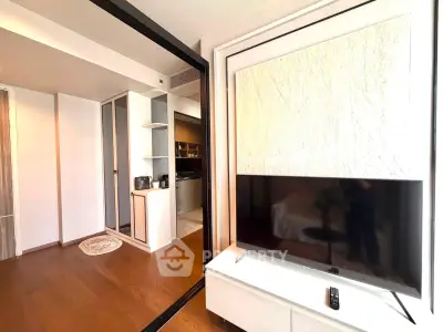 Modern living room with sleek TV setup and open kitchen layout in stylish apartment.