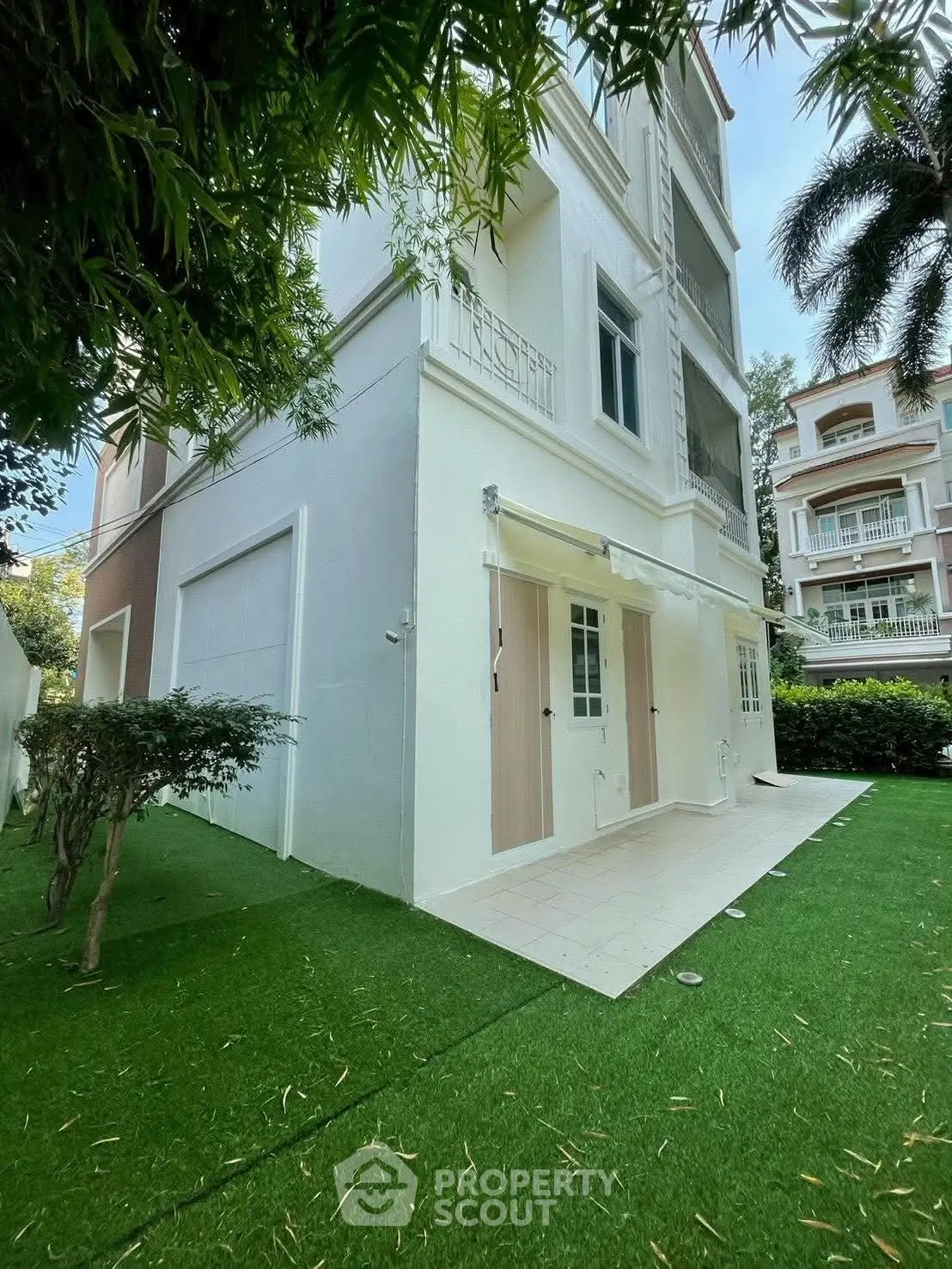 Elegant multi-story white building with lush green lawn and modern design.