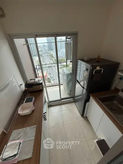 Compact kitchen with balcony view in modern high-rise apartment
