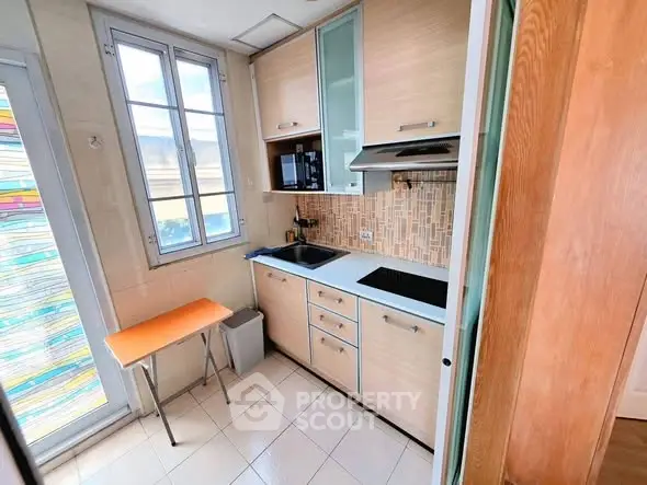 Charming compact kitchen with modern appliances and natural light, perfect for efficient cooking in a cozy space.
