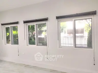 Bright interior with three large windows offering garden views, perfect for natural light lovers.