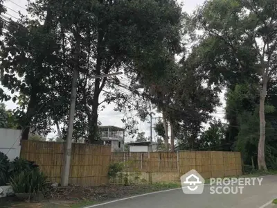 Scenic view of a residential plot with lush trees and bamboo fencing, ideal for development.