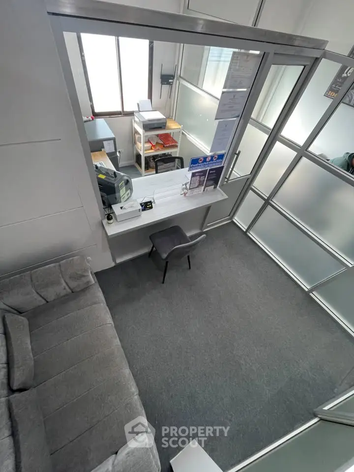 Modern office space with glass partitions and cozy seating area, ideal for productivity and comfort.