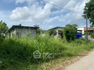 Charming rural property with lush greenery and rustic buildings under a bright sky.