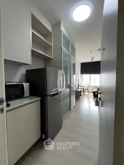 Modern compact kitchen with sleek appliances and open layout leading to a bright living area.