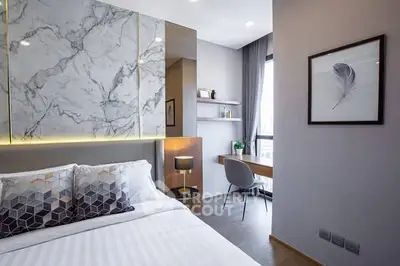 Modern bedroom with stylish decor and natural light, featuring a cozy workspace by the window.