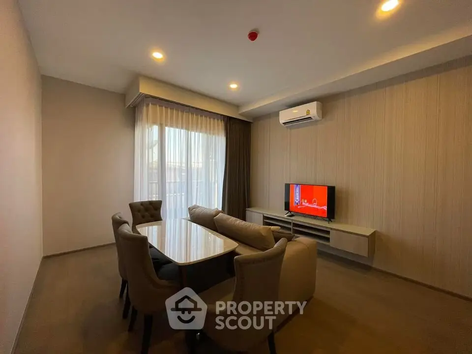Modern living room with elegant dining set and wall-mounted TV, featuring ambient lighting and air conditioning.