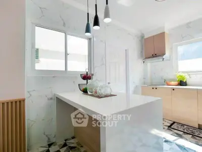 Modern kitchen with sleek island and stylish lighting in bright, airy space.