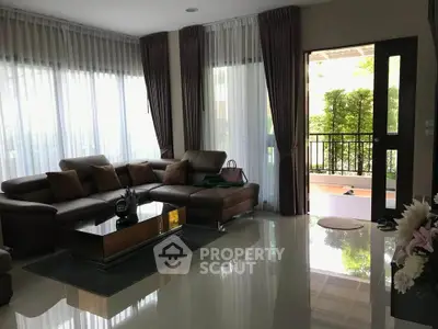 Spacious living room with elegant decor and large windows opening to a lush balcony view.
