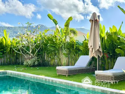 Luxurious tropical garden with pool and sun loungers, perfect for relaxation.