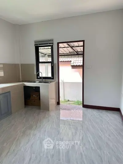 Bright kitchen with open layout and modern finishes, featuring a window and door leading to outdoor space.