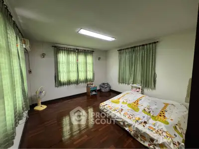 Spacious bedroom with wooden flooring and large windows for natural light