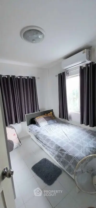 Cozy bedroom with single bed, air conditioning, and natural light from window.