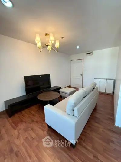 Spacious living room with elegant chandelier and modern furniture, perfect for relaxation and entertainment.
