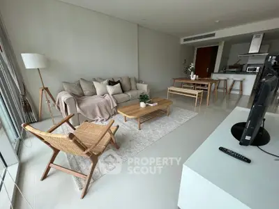 Spacious modern living room with elegant furniture and open-plan layout leading to a sleek kitchen, perfect for entertaining and relaxation.
