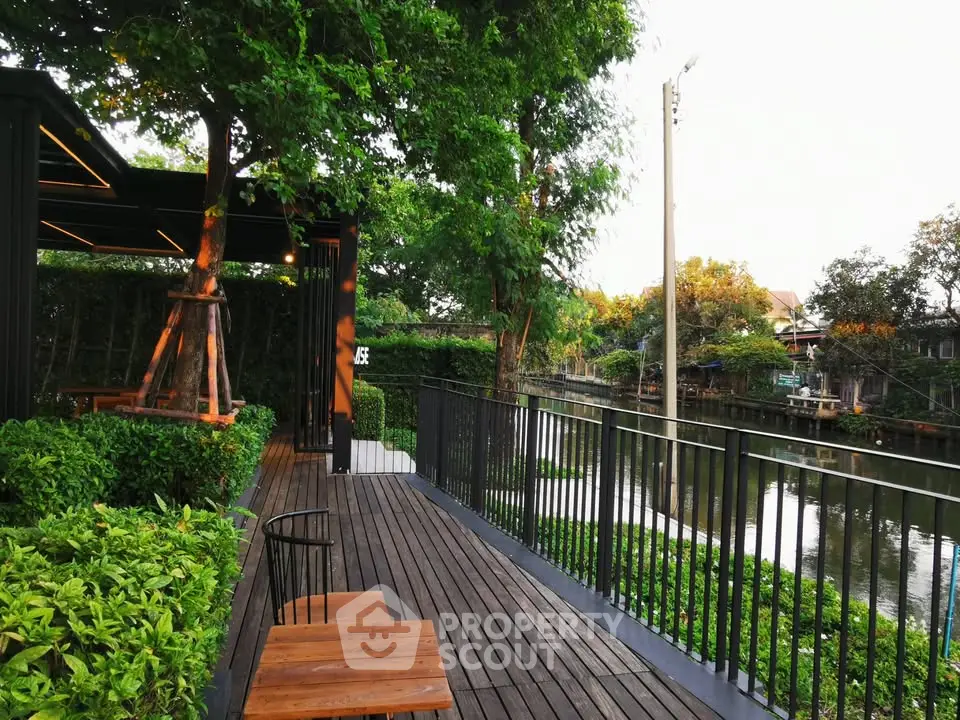 Charming riverside deck with lush greenery and serene water views, perfect for relaxation and outdoor enjoyment.