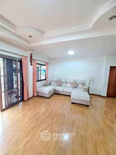 Spacious living room with elegant wooden flooring and cozy corner sofa, perfect for relaxation.