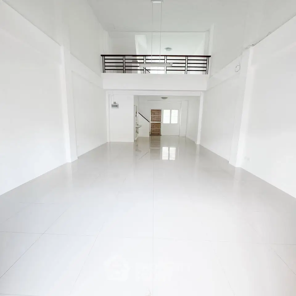 Spacious white interior with high ceiling and mezzanine, ideal for modern living.