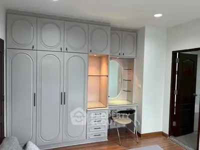 Elegant bedroom with built-in wardrobe and vanity, featuring modern design and ample storage space.