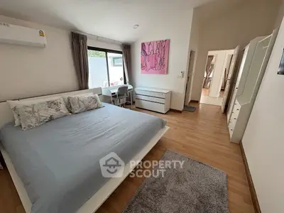 Spacious bedroom with modern decor and large window for natural light.