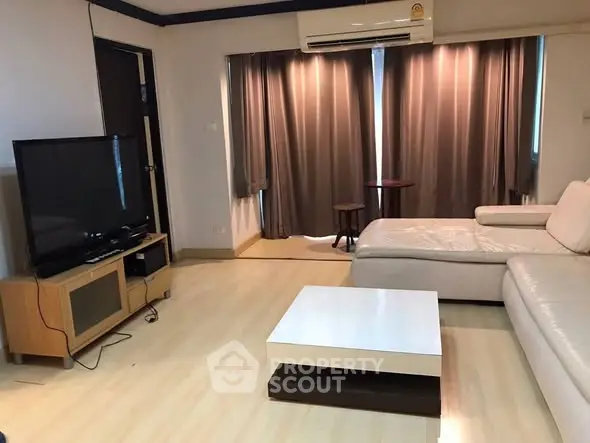 Spacious living room with modern furniture and large TV, perfect for relaxation.