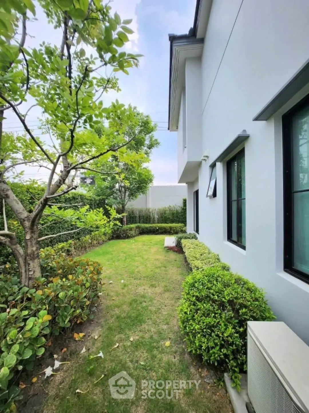 Charming garden view of modern home exterior with lush greenery and manicured lawn.