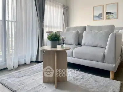 Modern living room with elegant gray sofa, stylish coffee table, and large windows with sheer curtains.