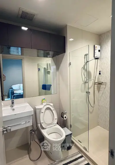 Modern bathroom with glass shower and sleek fixtures in contemporary apartment.