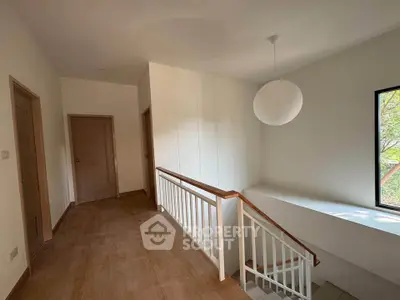 Spacious hallway with wooden flooring and modern lighting in a bright home interior.