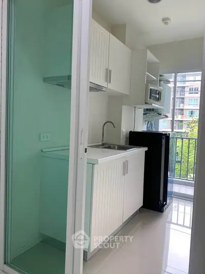 Modern compact kitchen with balcony view in urban apartment