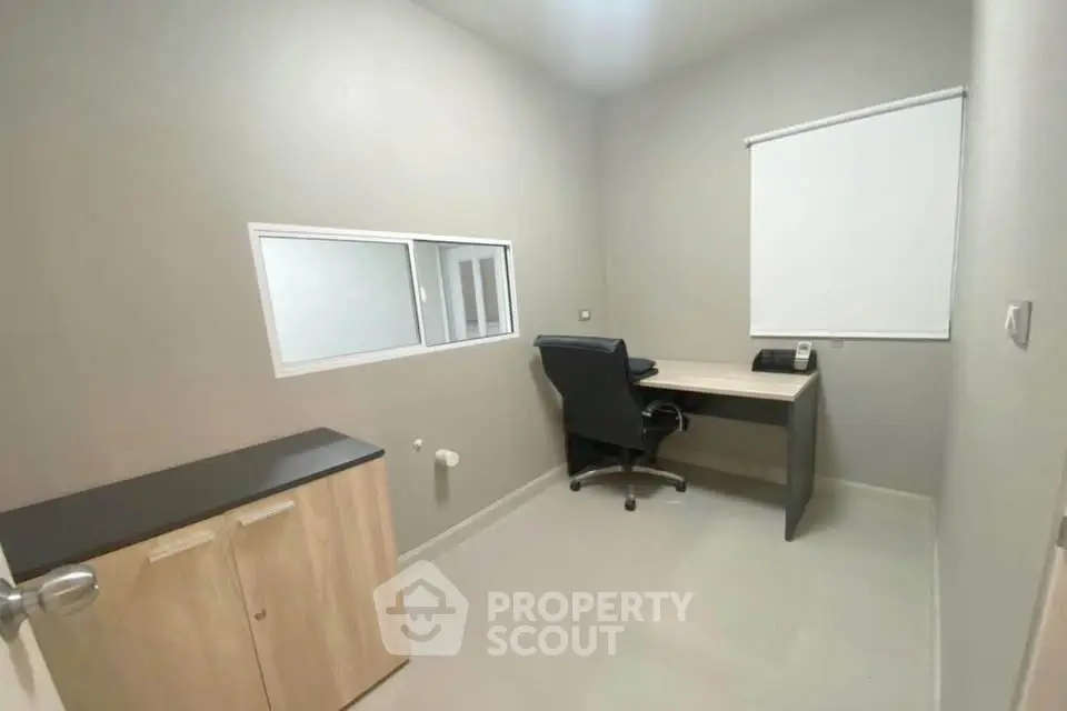 Compact study room with desk, chair, and cabinet in modern office space.