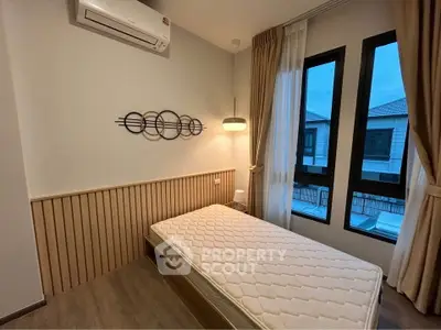 Cozy bedroom with modern decor and large windows offering natural light.