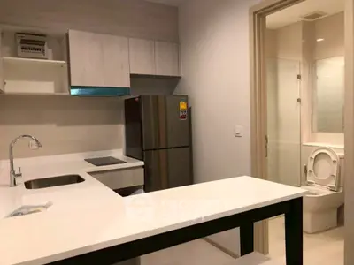 Modern kitchen with sleek design and adjacent bathroom, featuring stainless steel appliances.