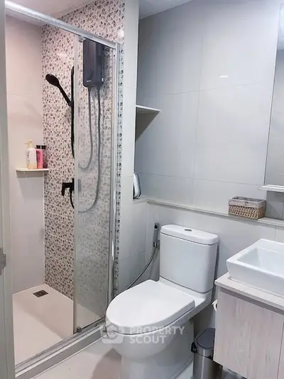 Modern bathroom with glass shower and sleek fixtures in contemporary home.