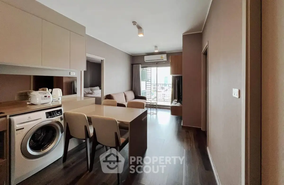Modern apartment interior with open kitchen and living area, featuring a washing machine and sleek furnishings.