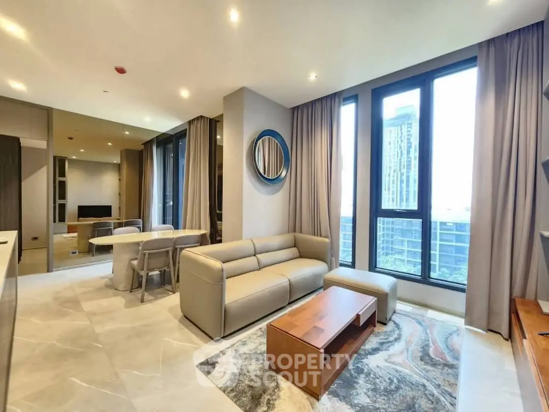 Modern living room with large windows and city view, featuring stylish furniture and elegant decor.