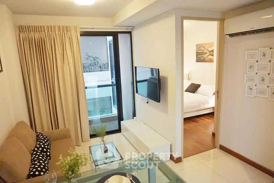 Modern living room with cozy sofa and TV, adjacent to a stylish bedroom.